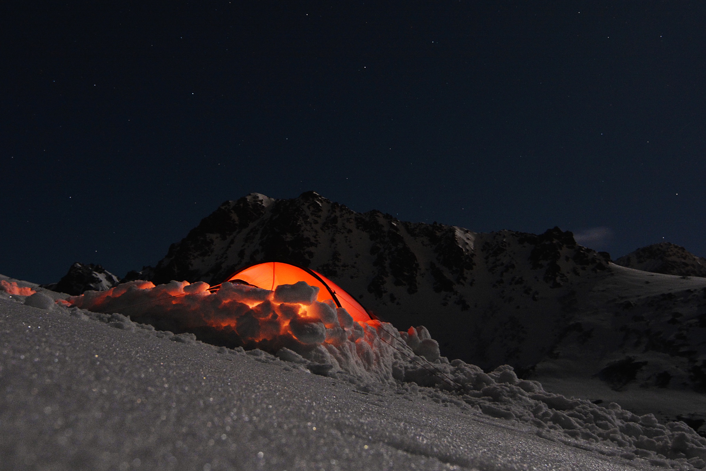 Una carpa iluminada de noche en un campamento de naturaleza