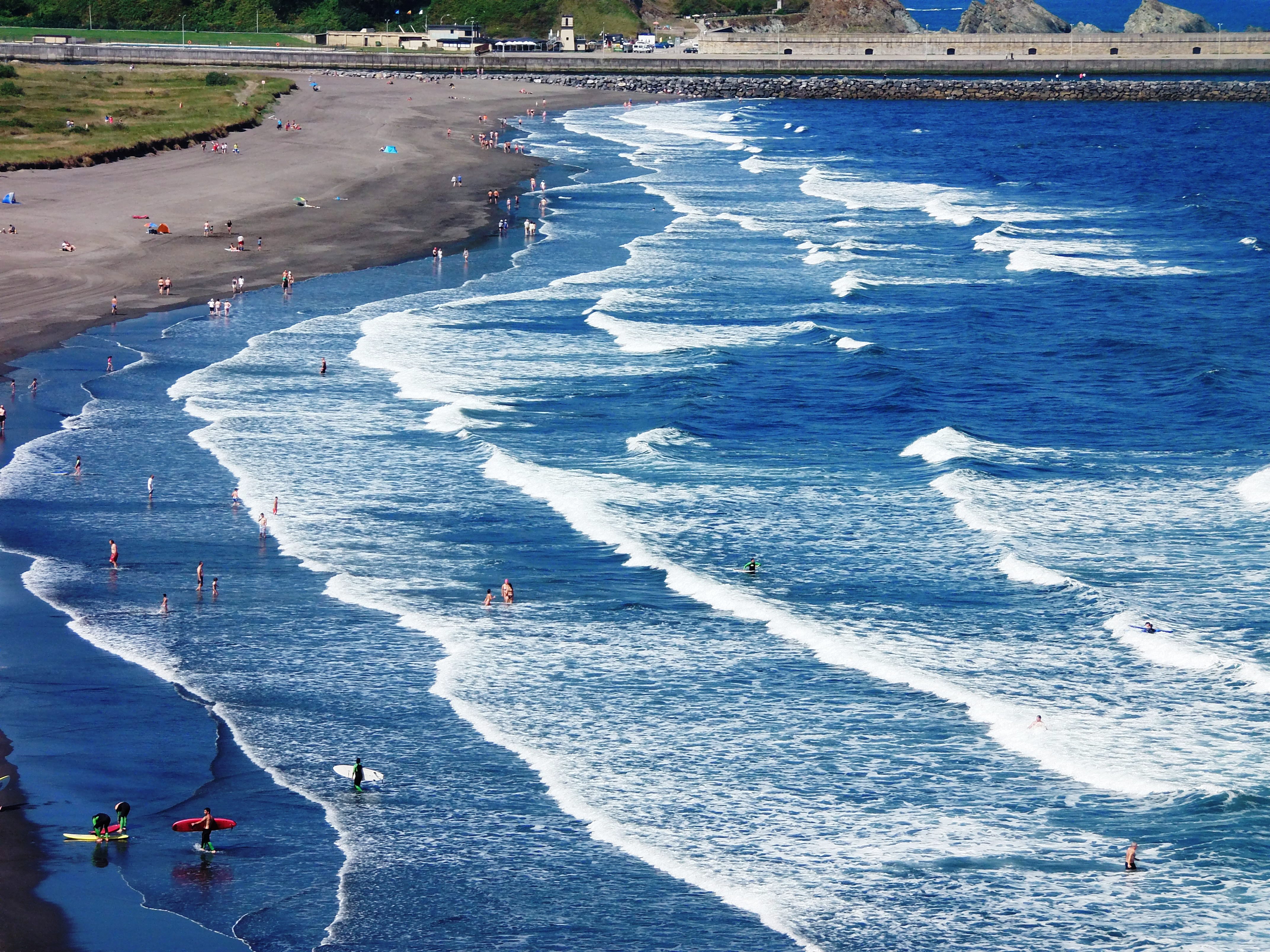 Beach with visible dark rip-current channels cutting through breaking waves
