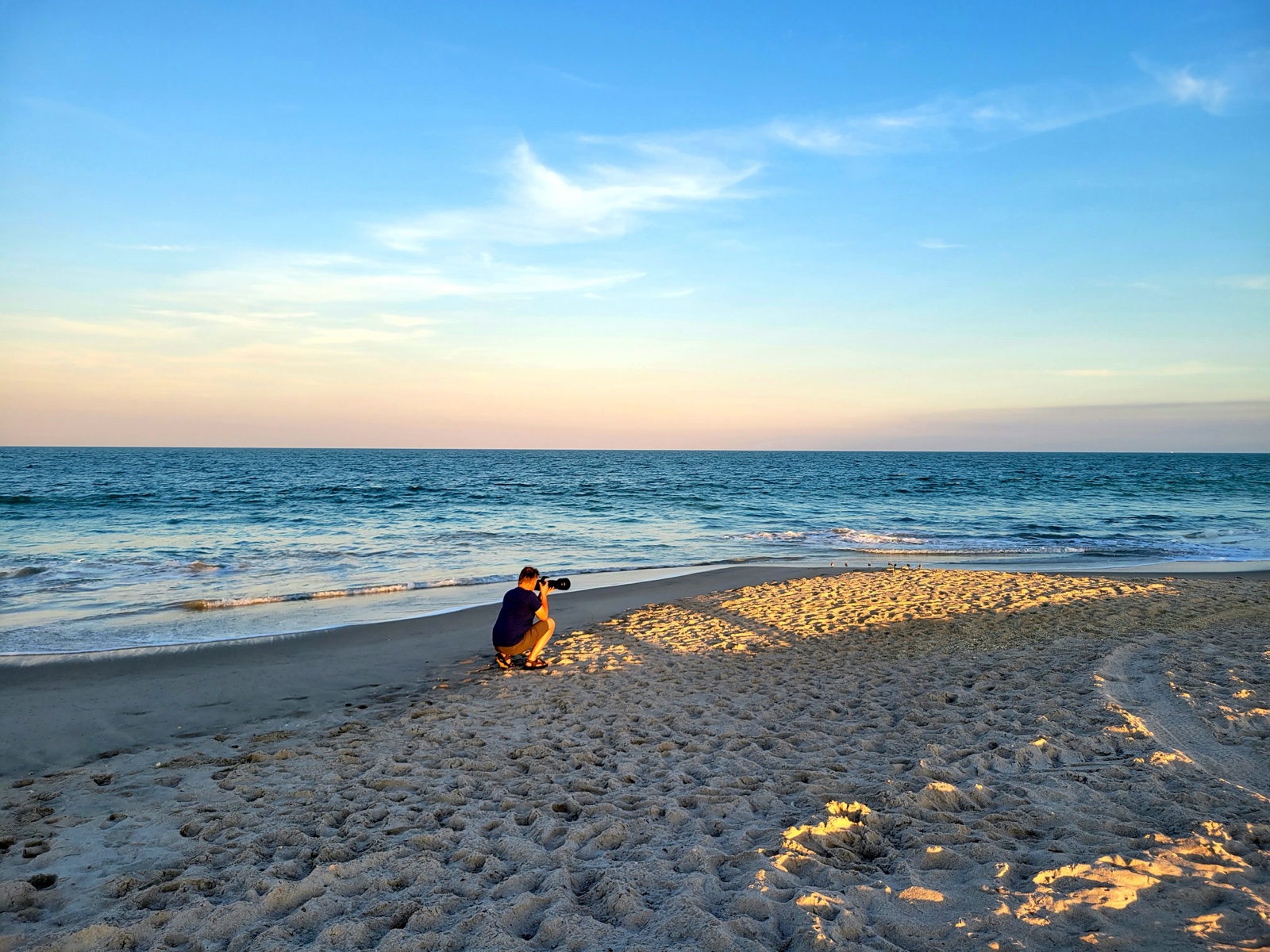 Photographer crouched on a Florida beach photographing wildlife at golden hour