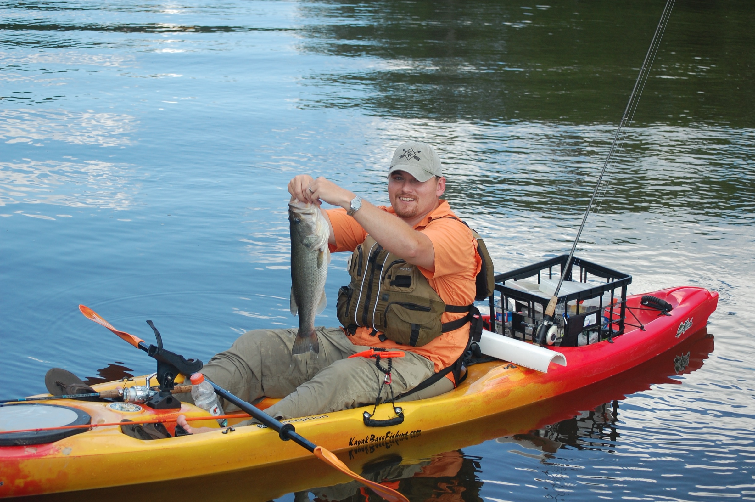 Angler in a rigged sit-on-top fishing kayak holding a freshwater bass on Bear Creek Lake, Virginia