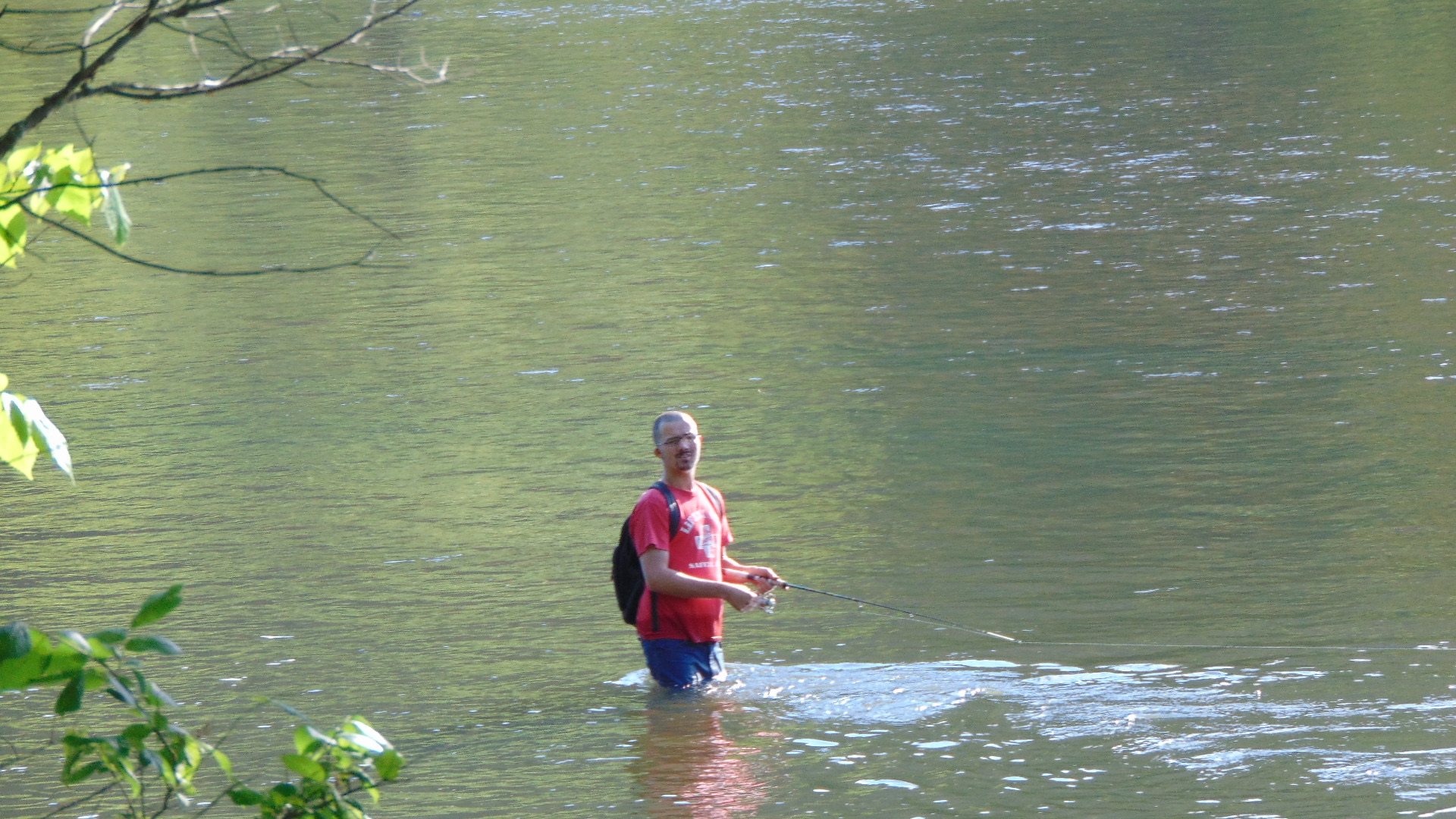 Angler wading in a river at Foster Falls, Virginia, holding a fishing rod while searching for smallmouth bass