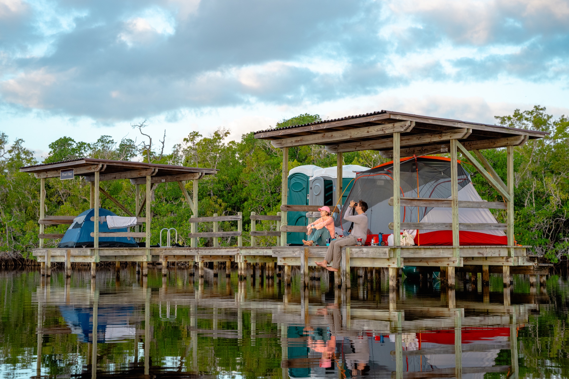 Campistas en una plataforma elevada sobre el agua en el Parque Nacional Everglades, Florida, con dos carpas montadas entre los manglares