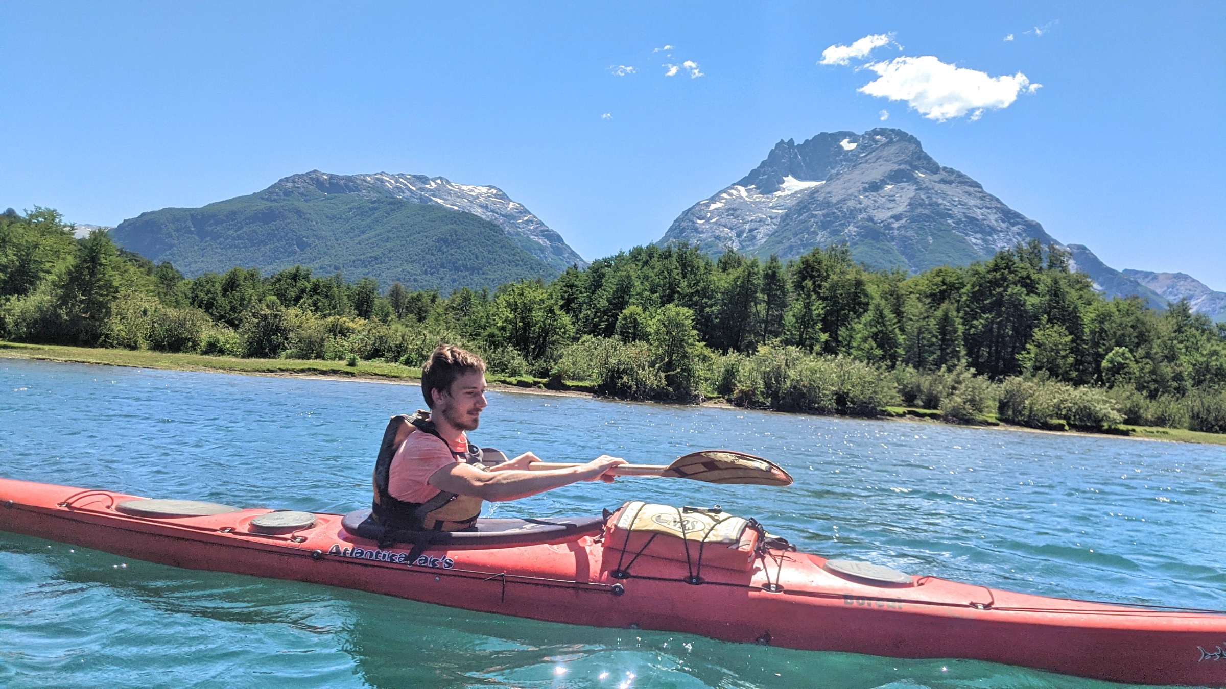 Man kayaking on a calm lake with a touring kayak