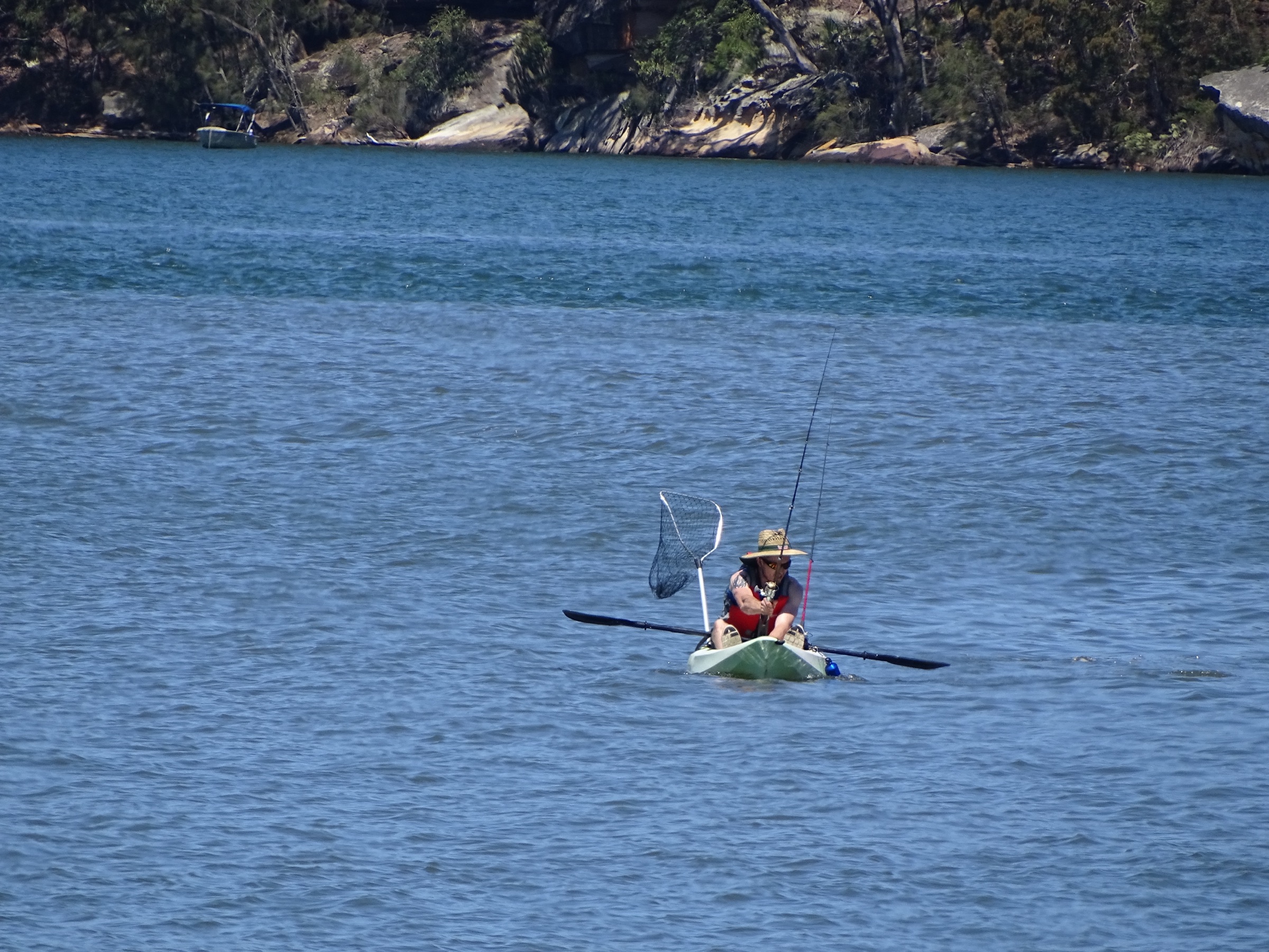 Angler fishing from a sit-on-top kayak on calm water
