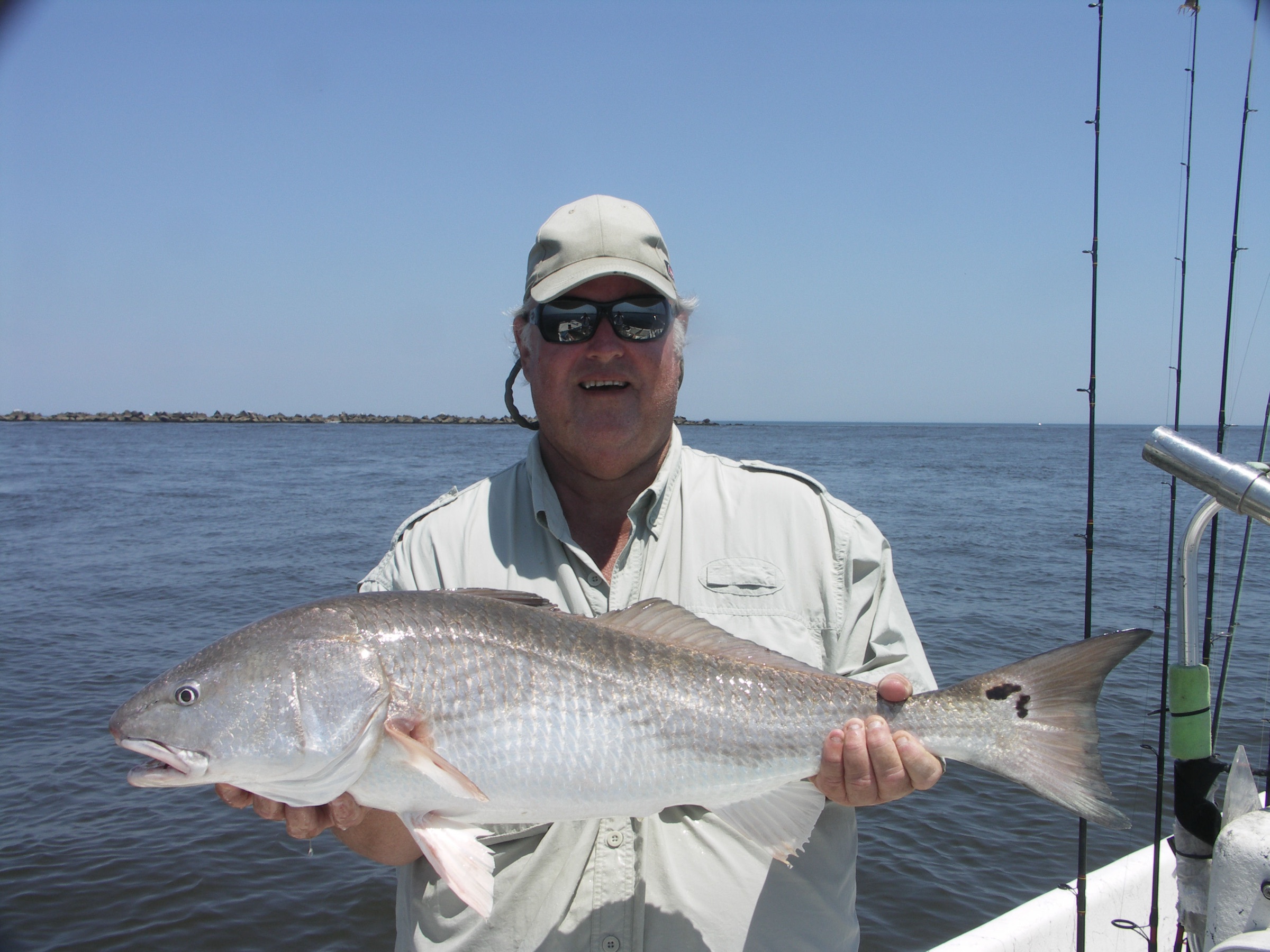 Un pescador sosteniendo un redfish capturado en los flats inshore cerca de Jacksonville, Florida
